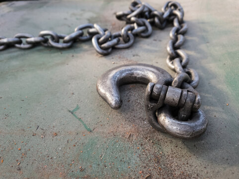Close up of an industrial metal hook and shackel on a chain