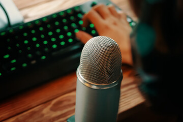 Man with headphones is typing on the keyboard and podcasting with retro old microphone. Radio show...