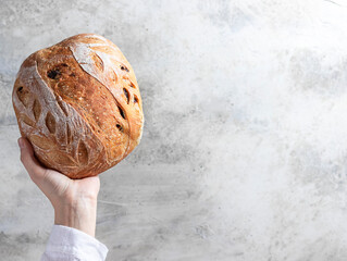 Female baker holds home made artisan organic bread fresh from the oven. Homemade sourdough bread....
