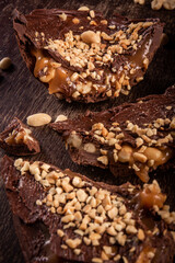 Stuffed chocolate easter egg with peanut and caramel on a wooden table with lots of peanuts around. Cracked.