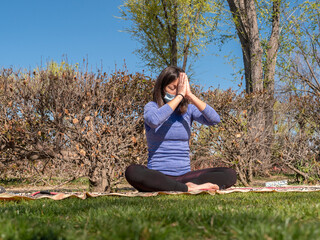 BRUNETTE WOMAN DOING YOGA IN PARK