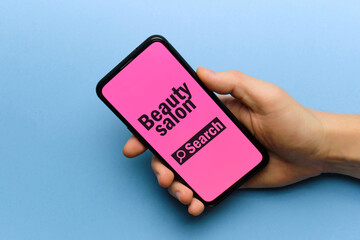 Person holding smartphone in hand with beauty salon search concept