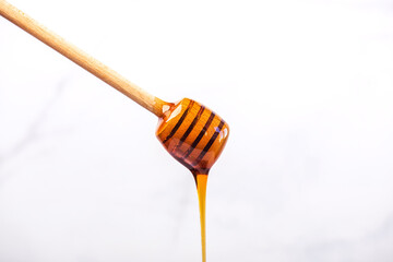 Honey dripping from a wooden spoon for honey