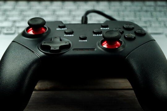 Black gamepad is lying on a laptop keyboard.The joystick for video games lies next to an open laptop. Professional gaming concept. Close-up.	