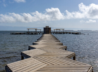 Fototapeta premium wooden boardwalk leading out into the ocean to a public bath installation