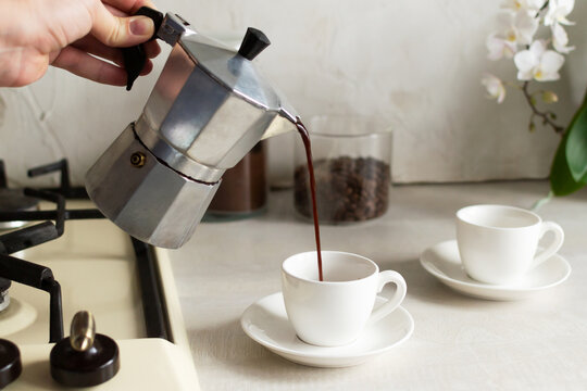 Coffee Is Poured From The Geyser Coffee Maker Into The Espresso Cup. The Concept Of Making Coffee At Home. Horizontal Orientation.