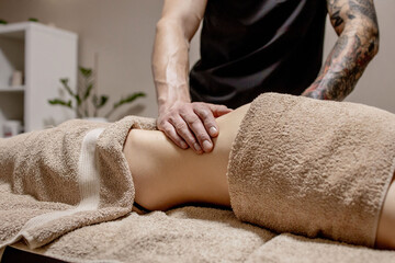 Young woman having abdomen massage. Masseur make massage for stomach