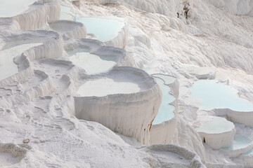 Beautiful bends in form of cloud of terraces with blue water on white mountain resort of Pamukkale in Turkey.