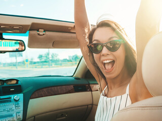 Portrait of young beautiful and smiling hipster female in convertible car. Sexy carefree woman...
