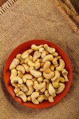 Peeled nuts in a clay plate on burlap on a wooden table.