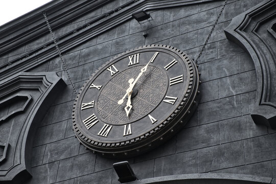Exterior roman numeral clock on facade of building. Vintage clock in railway station.