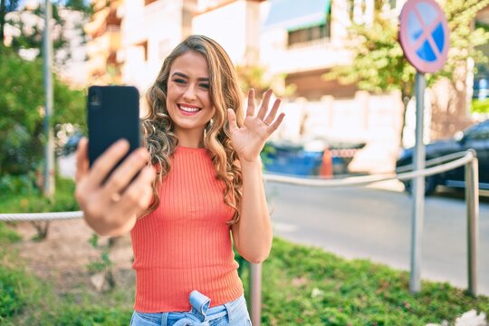 Young blonde girl smiling happy doing video call using smartphone at the city.