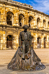 view of the Roman amphitheater in Nimes with the statue of the bullfighter Nimeno