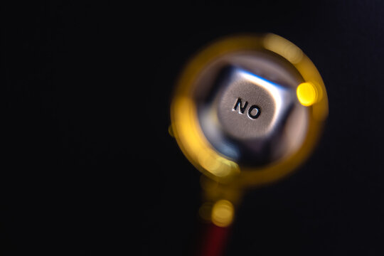 Under the magnifying glass, a close-up image shows the face of a dice with the inscription of word "no". The concept of yes-no choice.