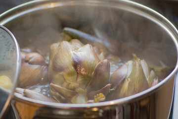Globe Artichokes (Cynara cardunculus var. scolymus), also known by the names French artichoke and green artichoke, being cooked in a pot with boiling water and lemons