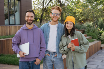 Group of smiling multiracial university student standing together, looking at camera, smiling....