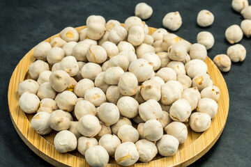 White chickpeas scattered on a black stone background.