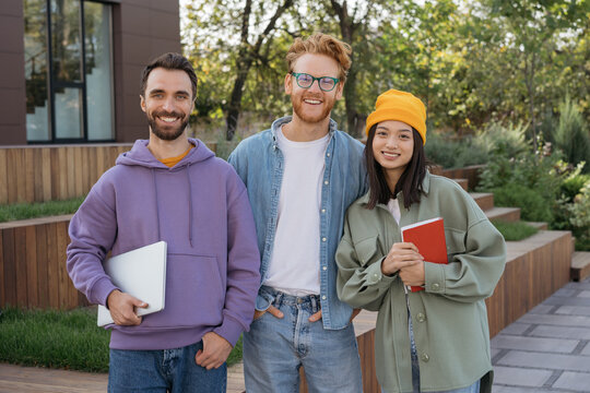 Group of smiling multiracial university student standing together, looking at camera, smiling. Portrait of happy successful team of young developers