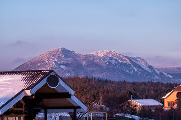 Mountains, forest and village on a winter evening