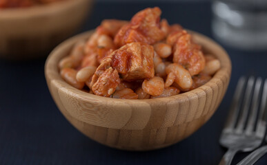 Pork stew with white beans in a wooden bowl.