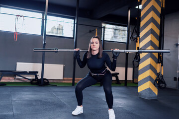sporty girl squats with barbell training.