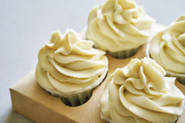 Paper box with cream cupcake. Birthday sweet bakery. Cookies four pack. Yummy buttercream dessert. Wedding party food. Grey background. Holiday recipe