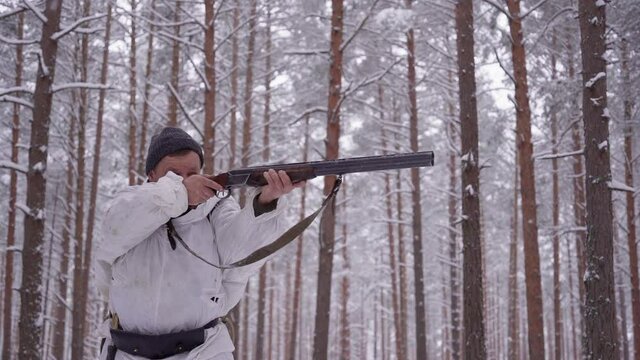 A hunter with a gun tracks down the prey. Aim a hunting rifle. Winter forest