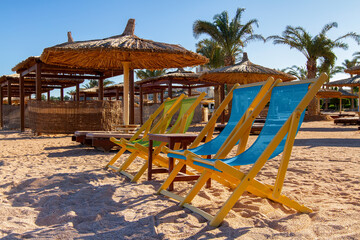 four sun loungers and a table on a deserted empty beach, sun loungers and umbrellas on the shores of the Red Sea, evening, winter Sharm el Sheikh, Egypt