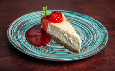 Slice of fresh delicious cheesecake with strawberry and leaf of mint
