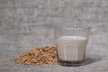 pile of raw oatmeal near a glass of milk. healthy breakfast. vegan oat milk.