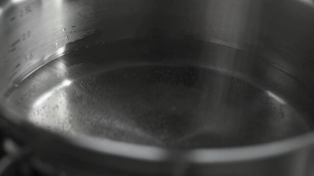 Extreme Close-up Of Adding Salt To A Pot Of Water For Cooking.