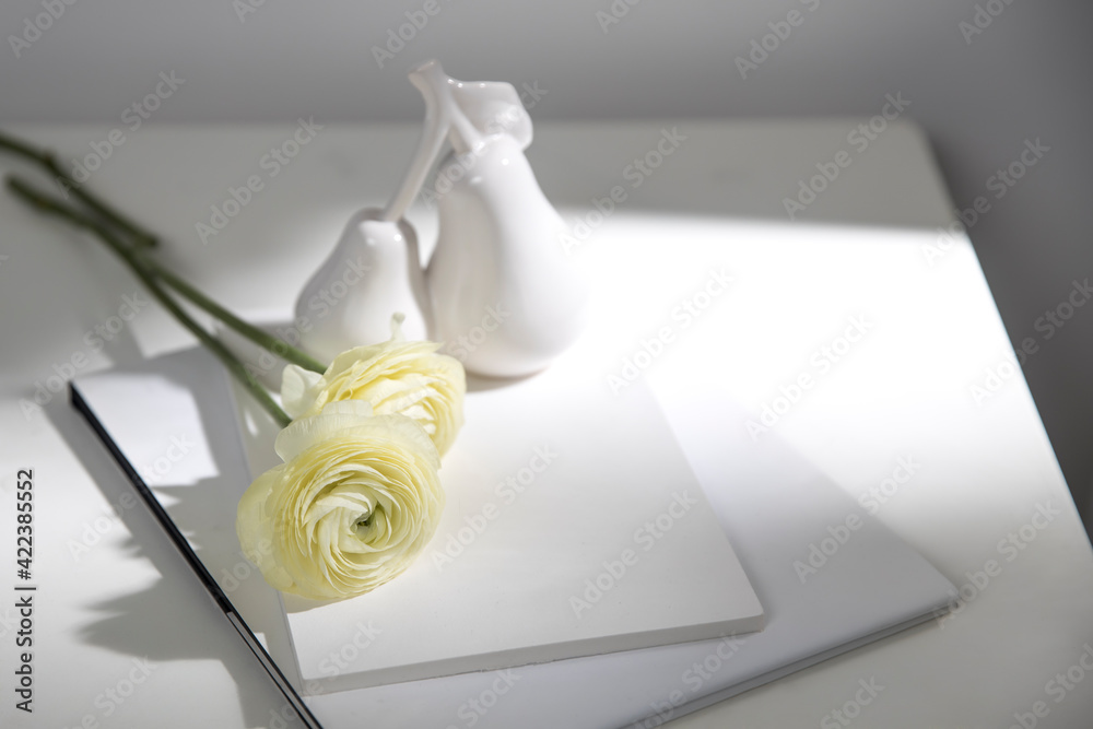 Wall mural Two white ranunculus with shadow on two white albums on the table. Copy space - Wall murals