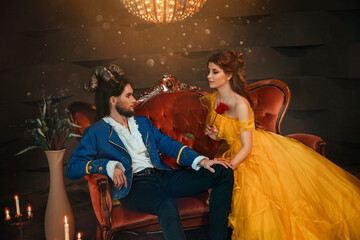 loving couple sits on medieval vintage sofa. Happy beauty woman fantasy princess in yellow dress...