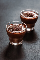 Homemade dark chocolate mousse in glasses on dark grey table