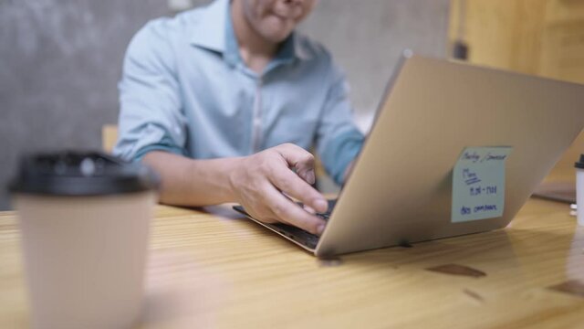 An Active Male Office Worker Typing On Laptop Keyboard While Sitting On A Chair In A Loft Style Room, Man Works With Passion, Reaching Out Hand Grab On A Take Away Paper Cup, Sipping Coffee On Brake