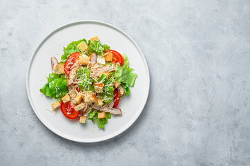 Classic Caesar salad with chicken breast on a gray background.