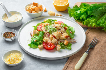 Fresh, delicious Caesar salad, sauce, cheese and lettuce on a gray background.