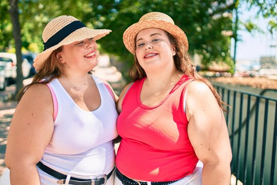 Two plus size overweight sisters twins women hugging together outdoors