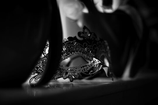 A black and white portrait of a venetian mask lying on a marble windowsill ready to put on and go to a masked ball, halloween party or carnaval.