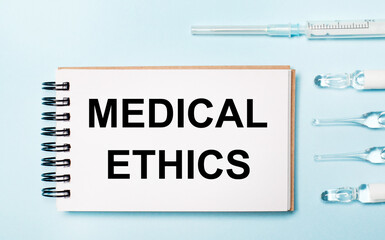 On a blue background ampoule with medicines and a notebook with the text MEDICAL ETHICS. Medical concept