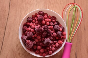 colored hand mixer and bowl with a frozen red berries