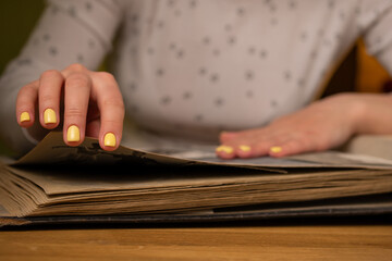 Woman looks through an family album with old photos at table at home.