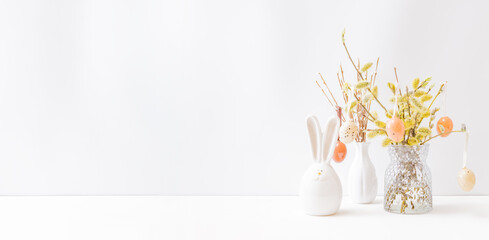 Home interior with easter decor. Willow branches in a vase, easter eggs on a light background