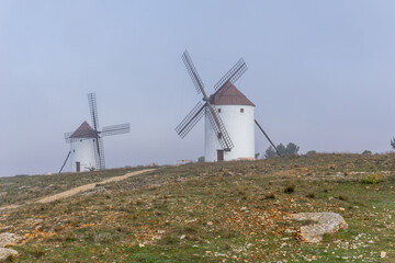 whitewashed windmills in La Mancha on a foggy morning