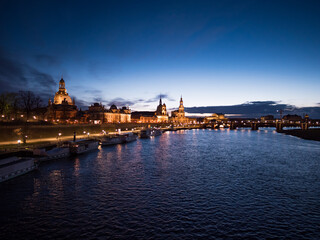 Dresden city elbe river after sunset in the blue hour. Illuminated skyline when the sun is going down in the evening. Beautiful old buildings and steamboats in the cityscape.
