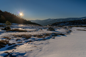 panoramic view of the sunrise or sunset of the sun over the mountains with a snow lake 