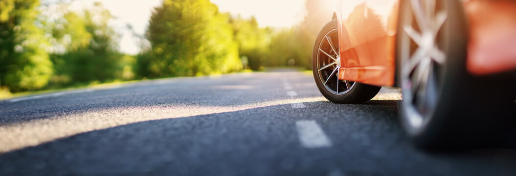 Red car on asphalt road in summer
