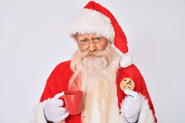 Old senior man with grey hair and long beard wearing santa claus costume eating cookies depressed and worry for distress, crying angry and afraid. sad expression.