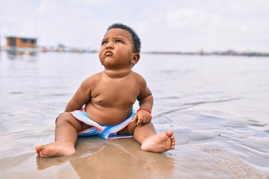 Adorable african american toddler sitting at the beach.