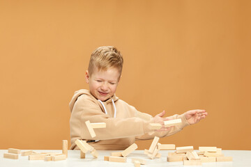 children plays with wooden constructor on desk.